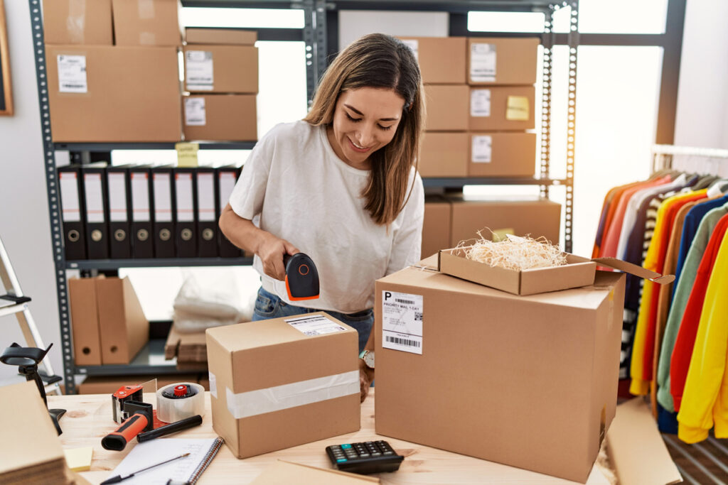 Young woman preparing boxes to ship