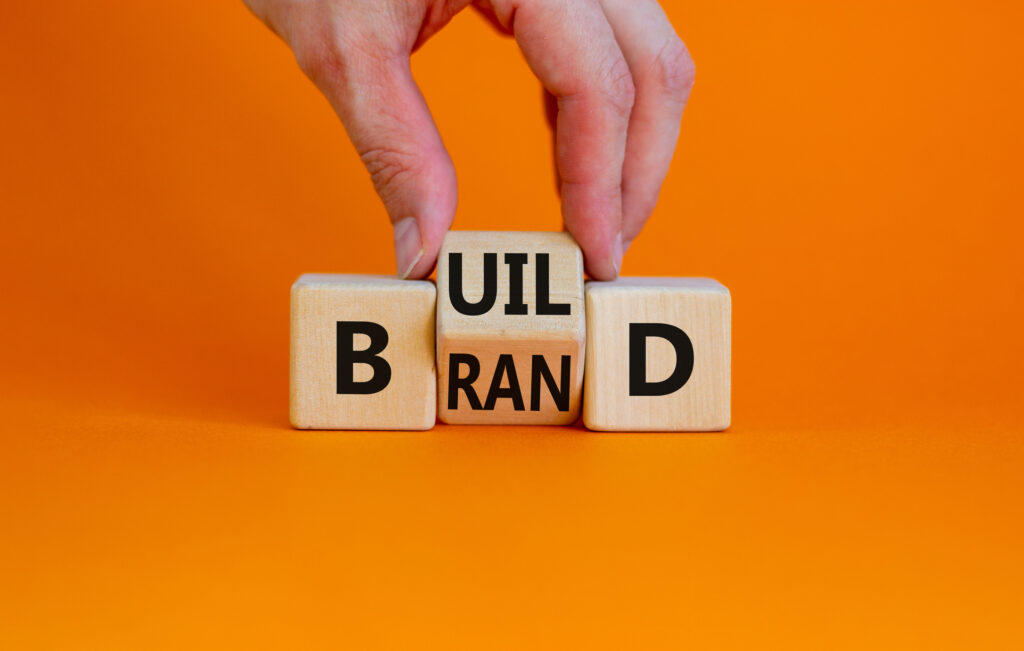 Hand Turning Word and Letter Blocks to Spell Out Brand.