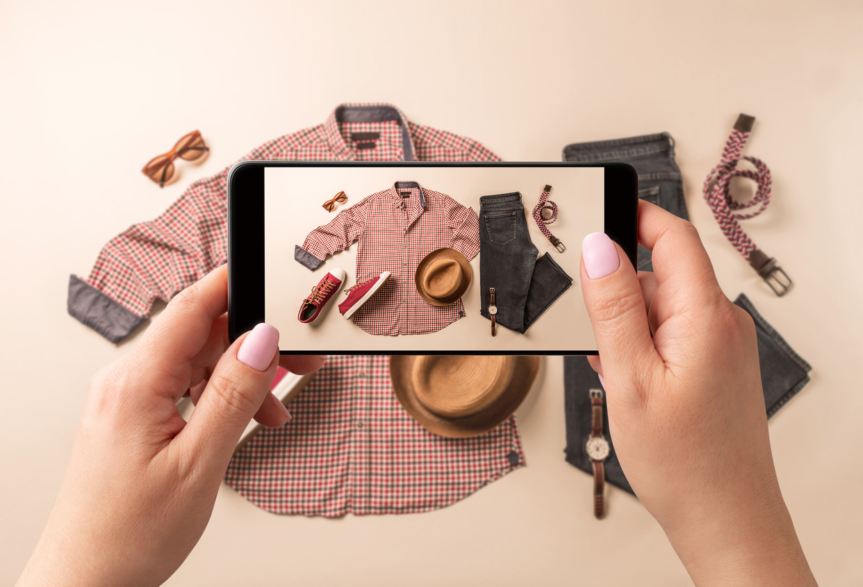Image of a person taking a picture of clothing with their phone to post on social media.