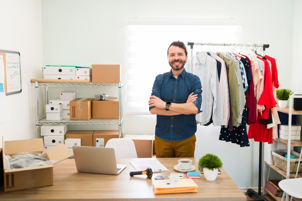Male entrepreneur standing surrounded by product in an office.